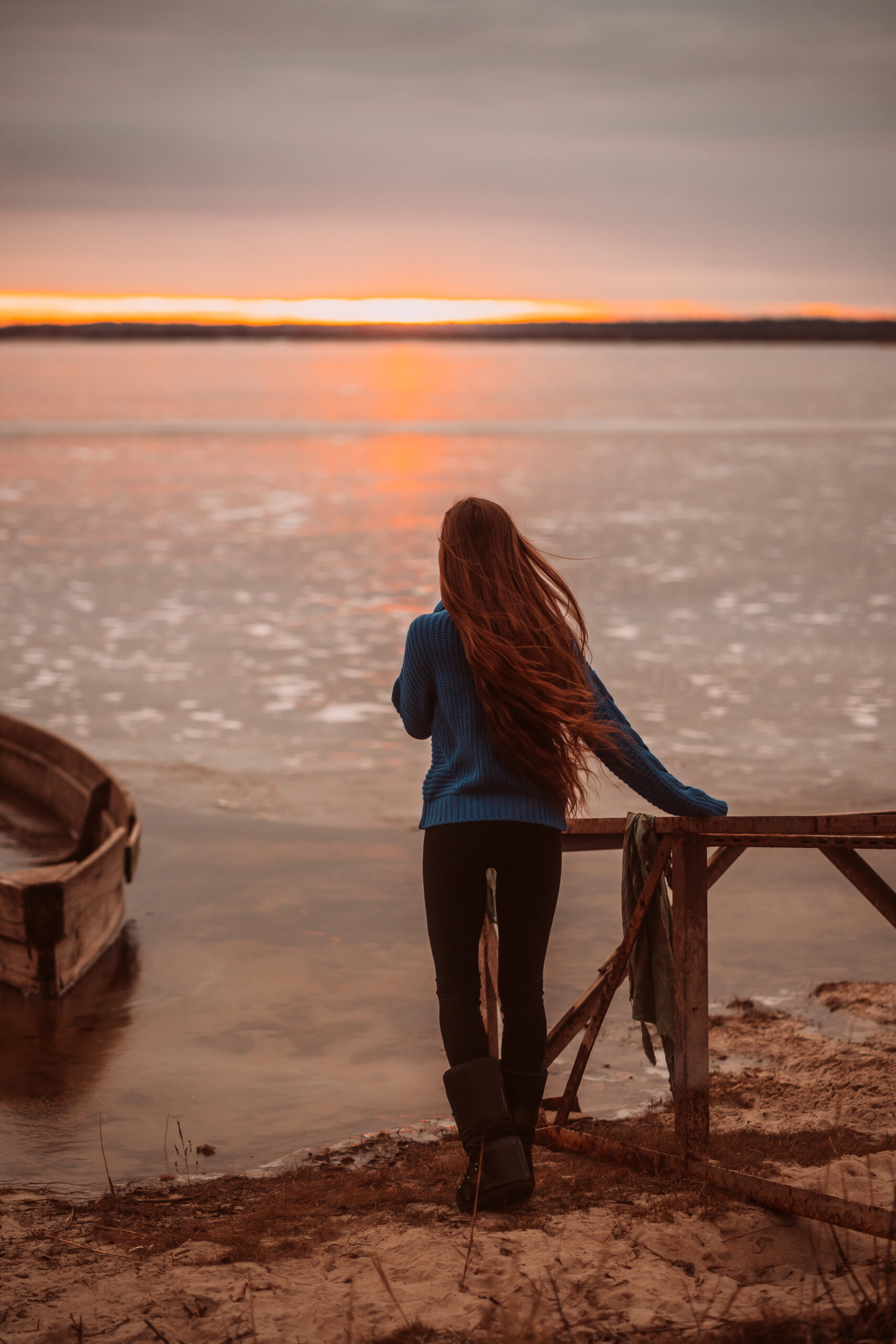 Woman enjoying time relaxing by the beautiful lake at sunrise.